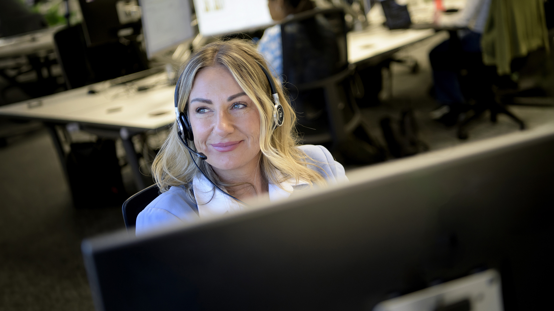 Woman wearing a headset sat at a computer.