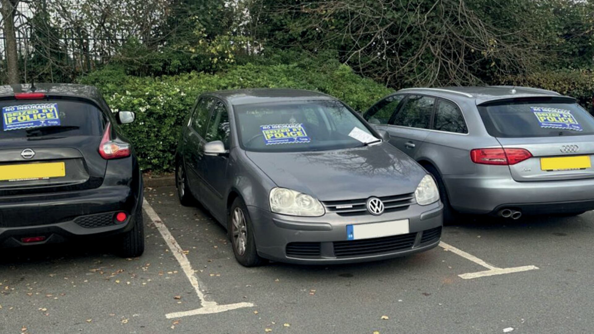 Three cars that have been seized in a car park.