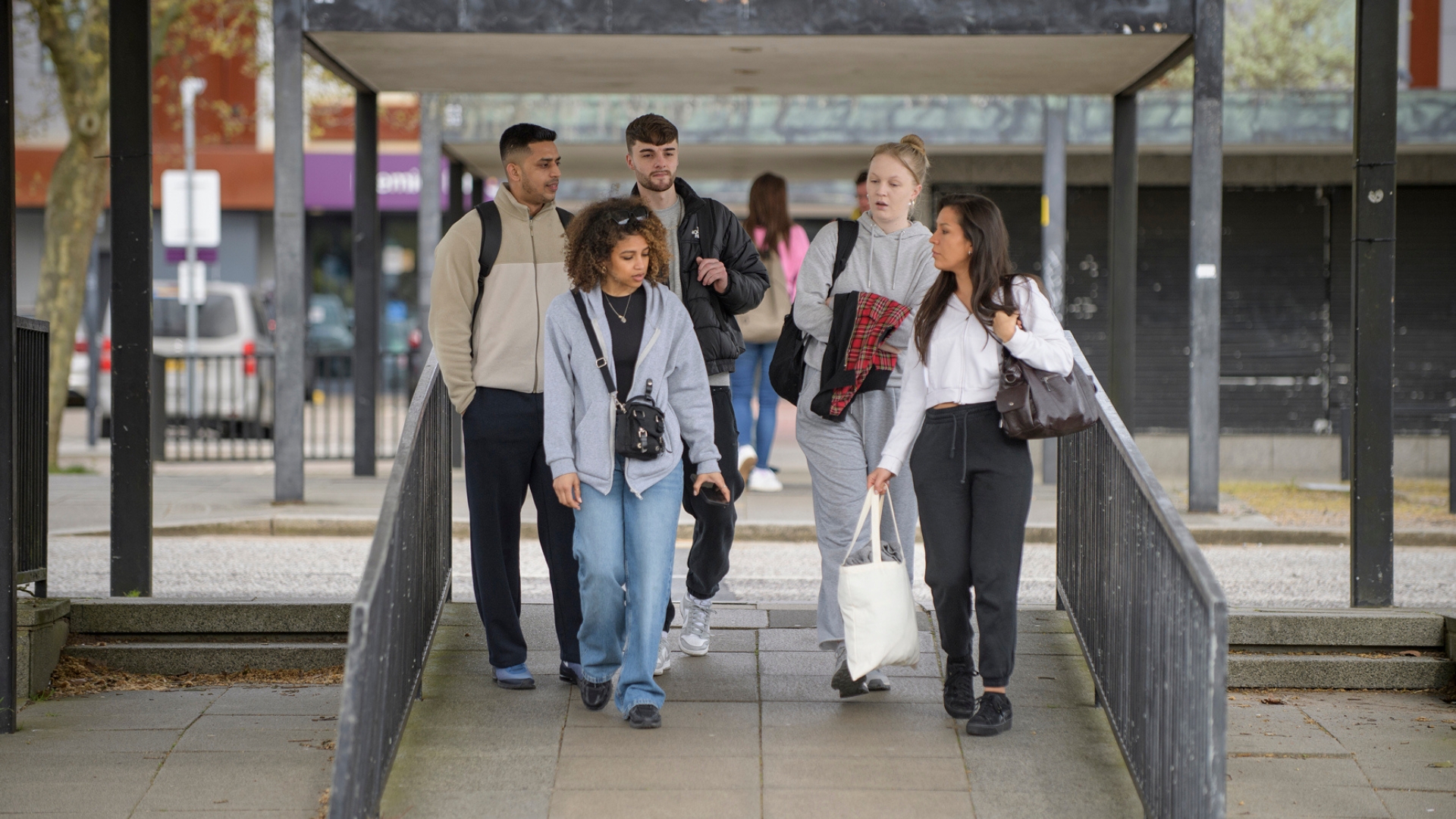 Five people walking together down a ramp in an urban area.