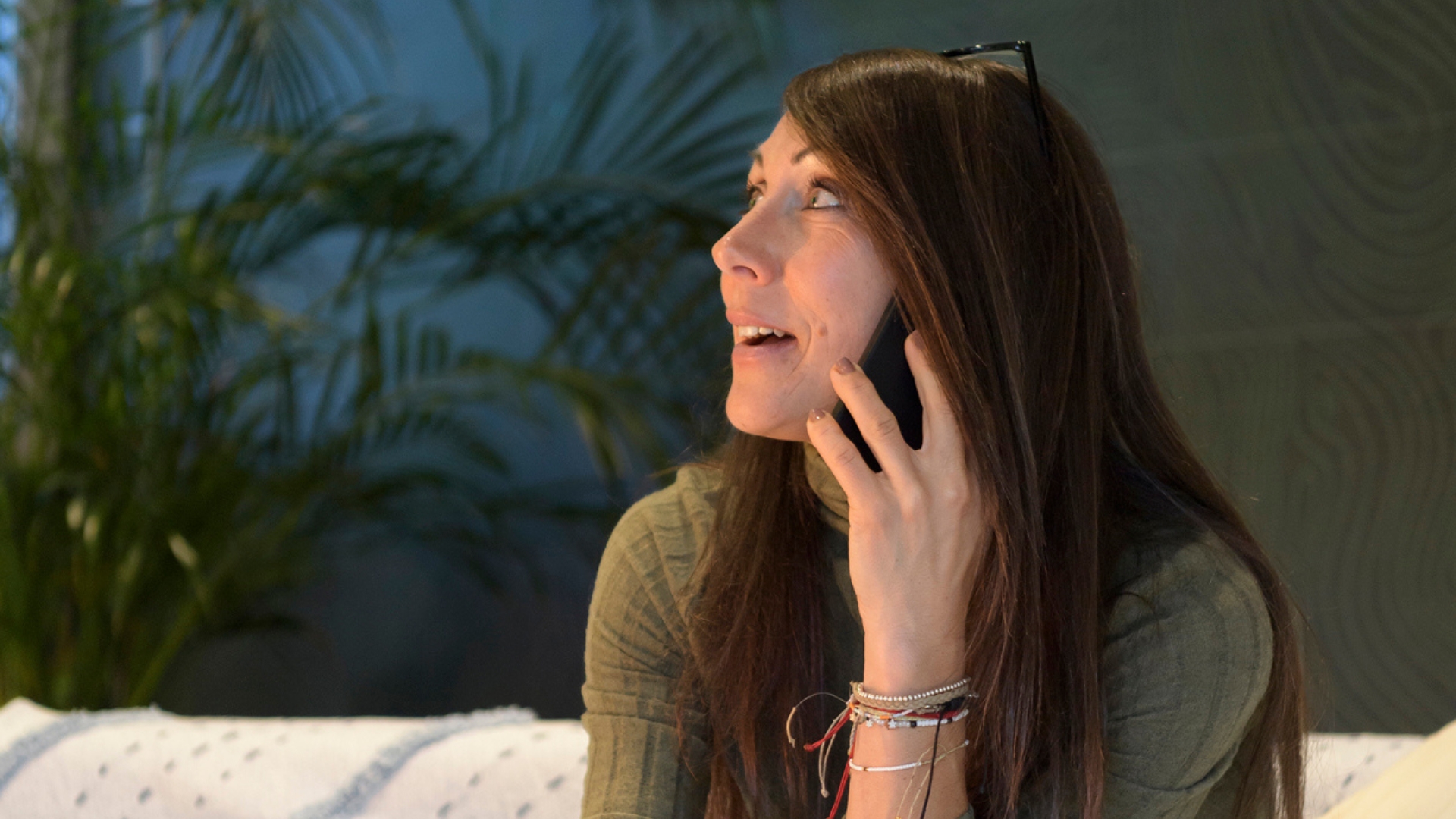 A person sitting on a sofa talking on a phone at home.