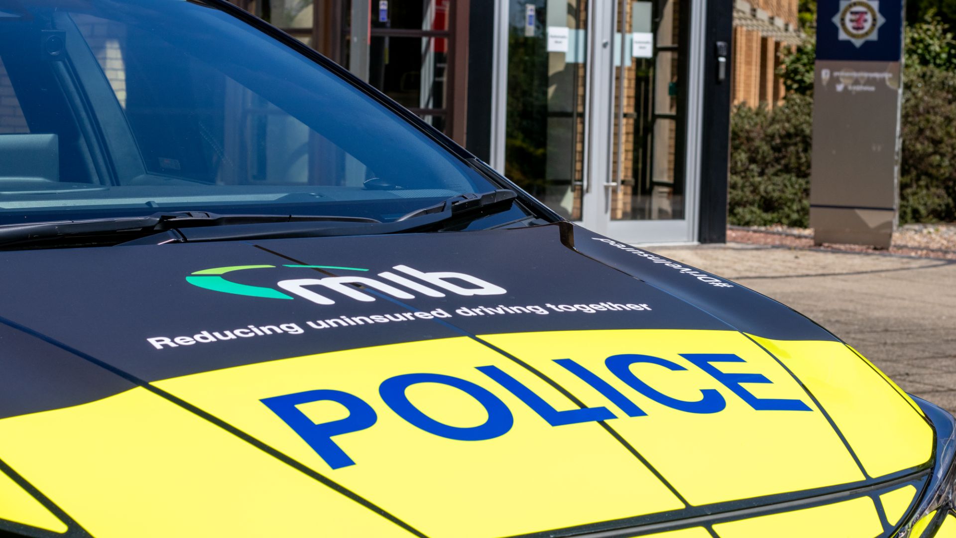 Bonnet of a dual-branded police car, showing MIB logo and 'reducing uninsured driving together' alongside POLICE branding.