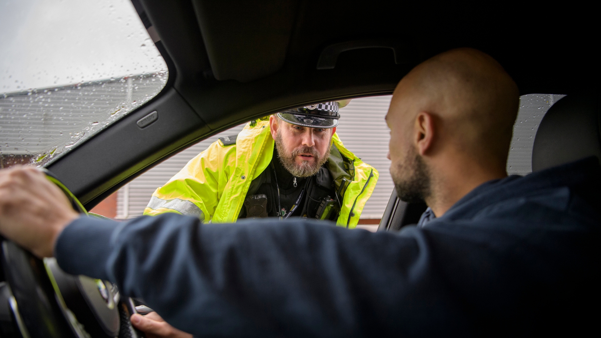 Police officer speaking to a driver during a roadside check.