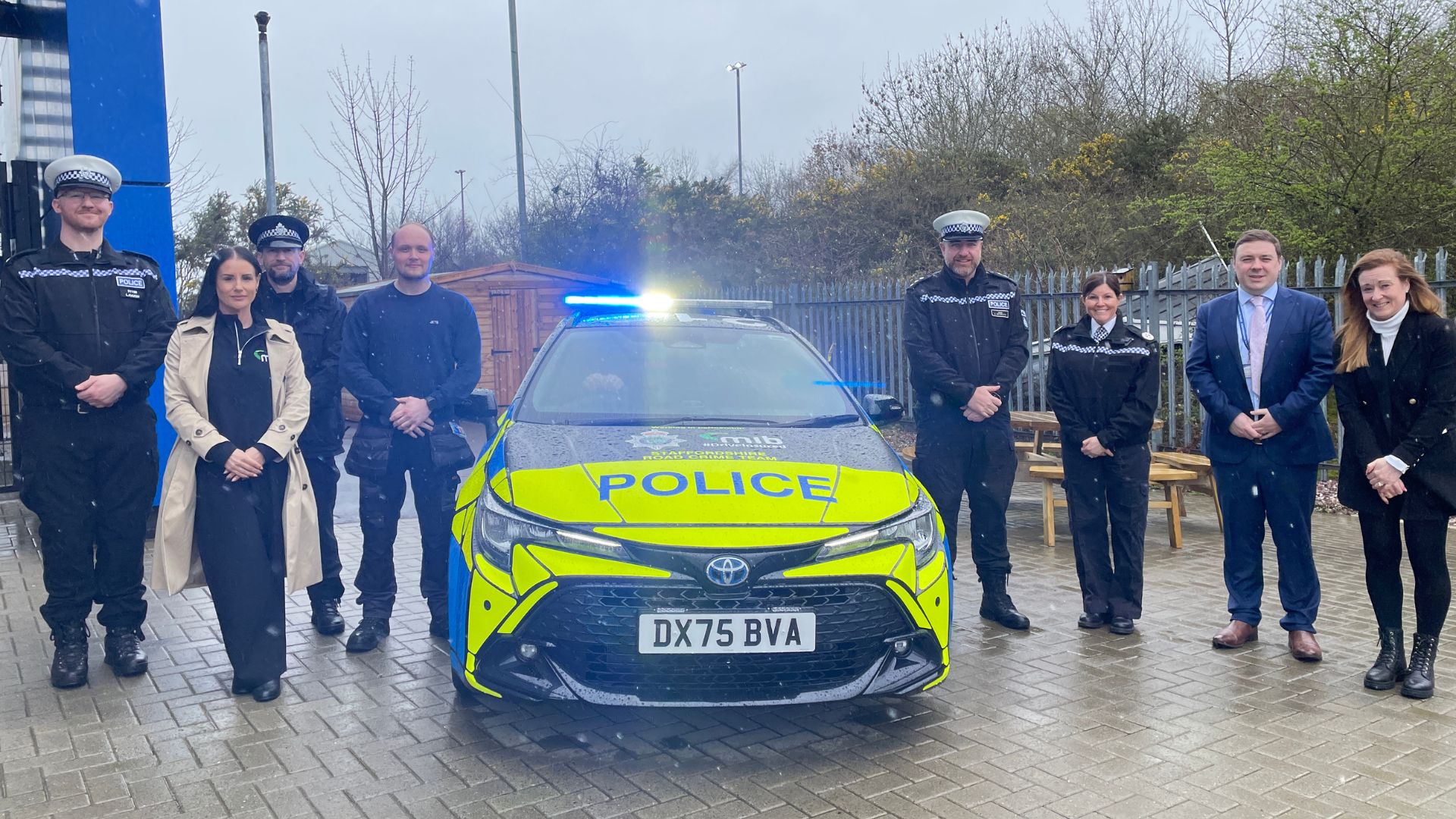 MIB branded police car with officers as a key handover ceremony.