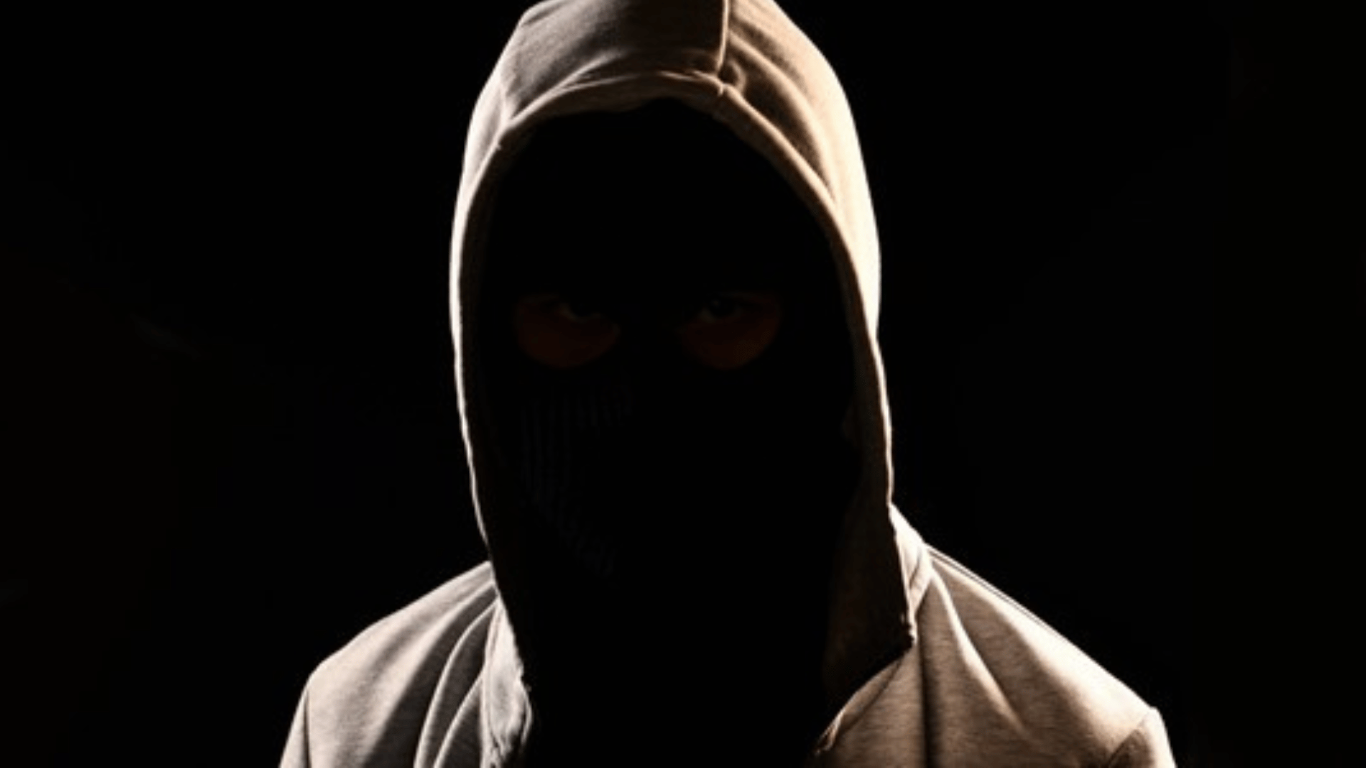 Person wearing dark hoodie and not showing their face on black background.