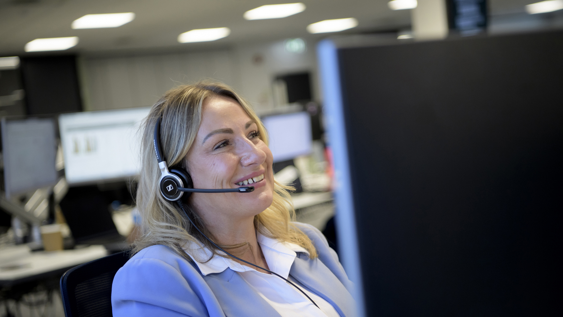 A person wearing a headset looking at a computer screen in an office.