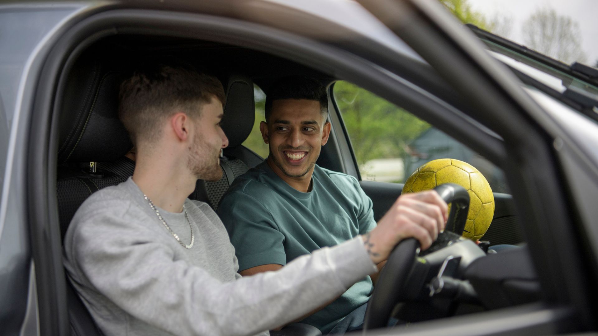Two young men inside the front of a car.