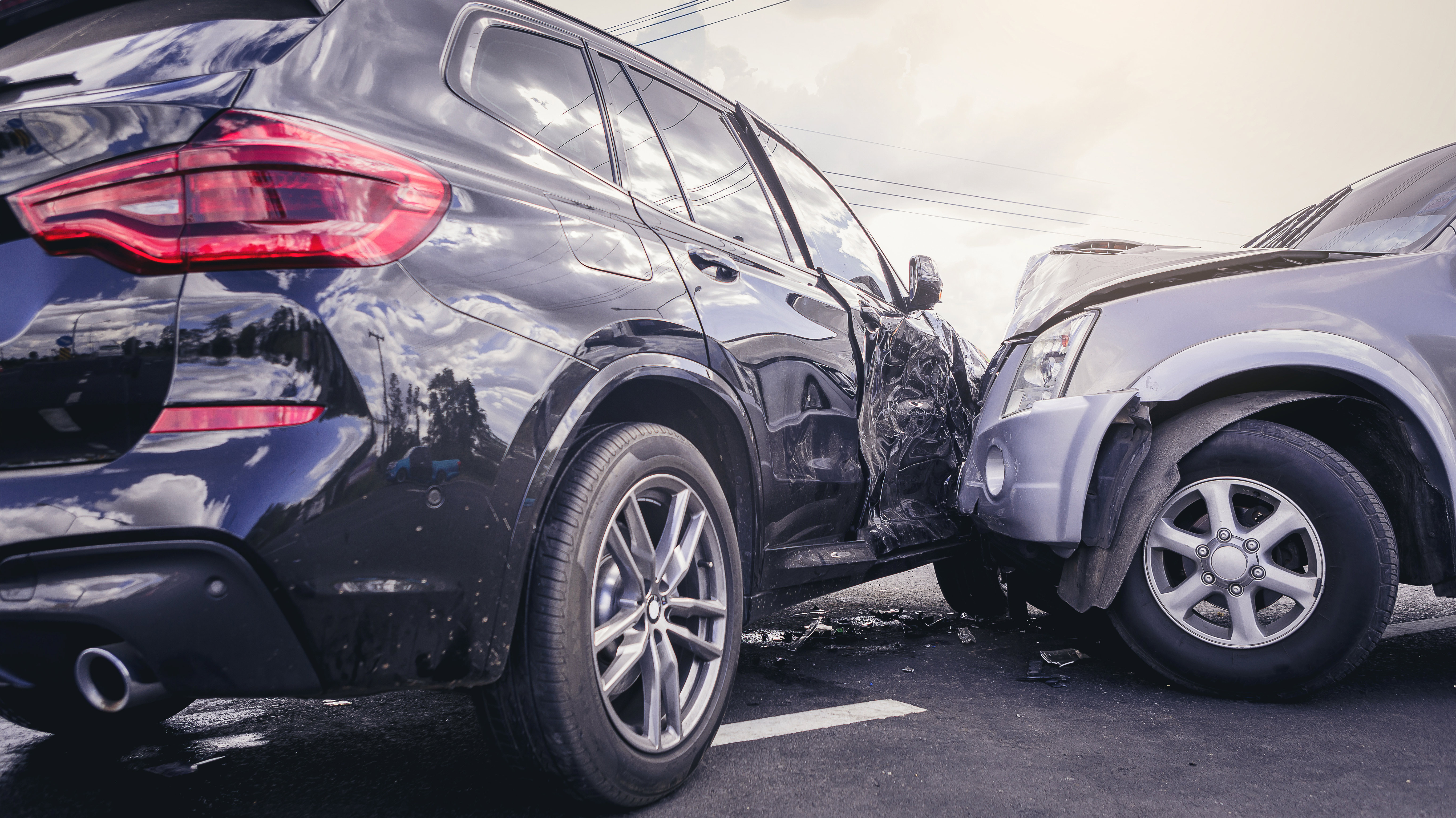 Two cars after a collision, with visible side damage and debris on the road.